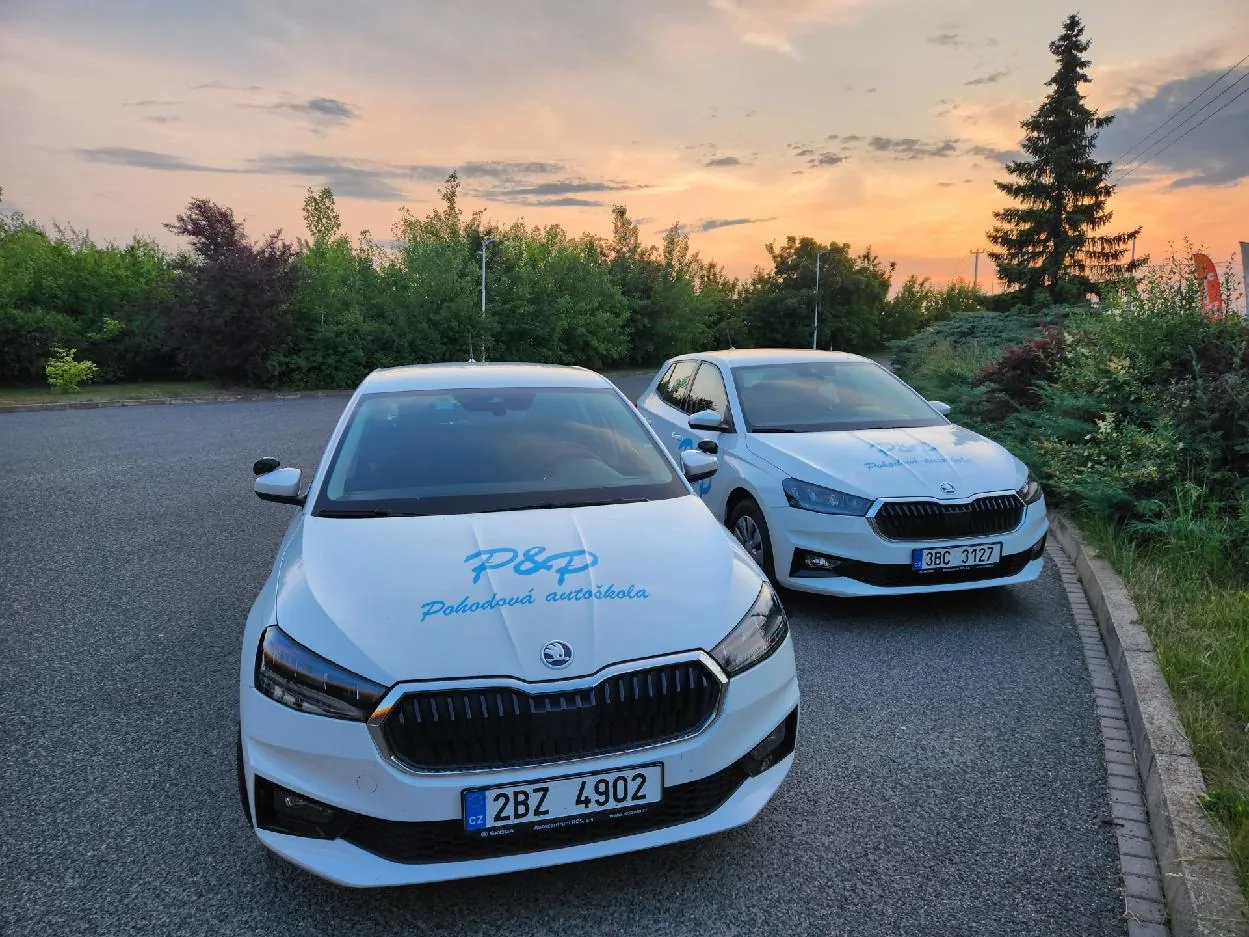 Két fehér Škoda Fabia tanulóautó a P&P Pohodová autoškola logójával a parkolóban naplementekor